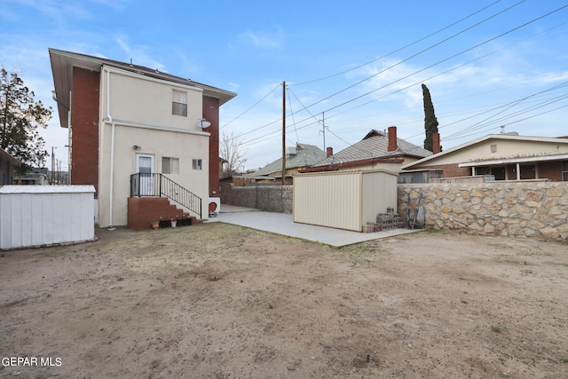 rear view of house with a patio and a shed