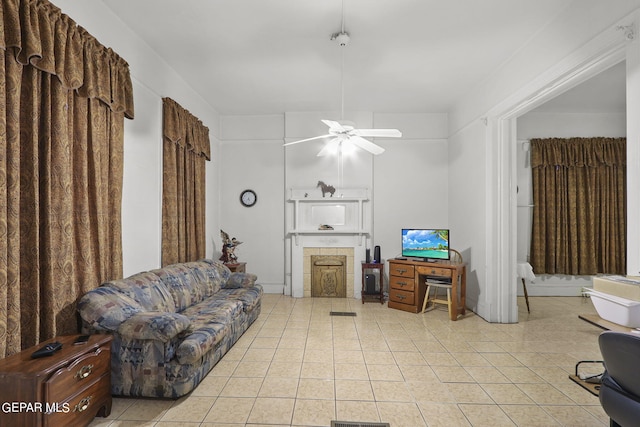 tiled living room featuring a fireplace and ceiling fan