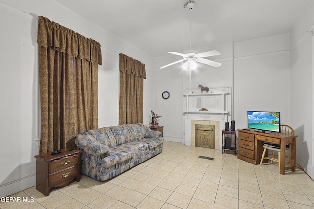 living room featuring light tile flooring, a fireplace, and ceiling fan