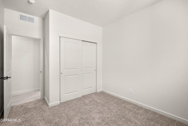 unfurnished bedroom with a closet and light colored carpet