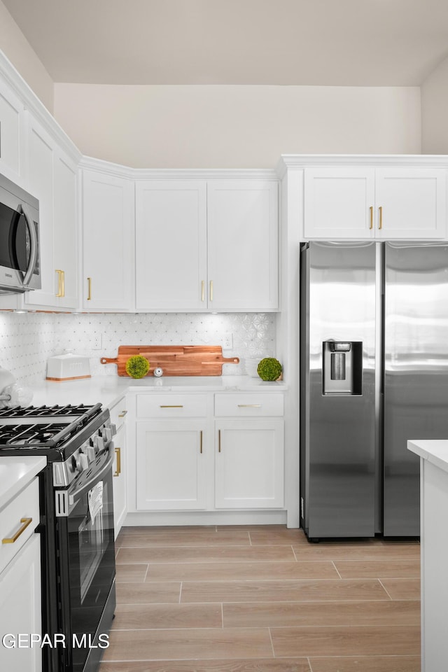 kitchen with white cabinets, appliances with stainless steel finishes, and backsplash