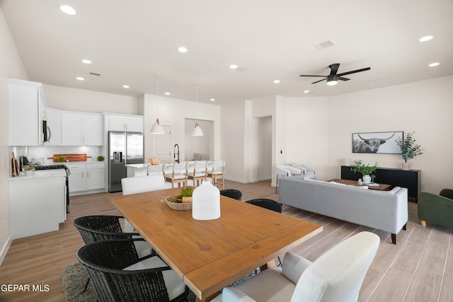 dining space featuring light wood-type flooring, ceiling fan, and sink