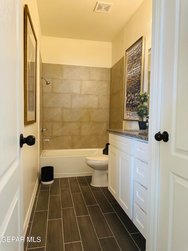 full bathroom with tiled shower / bath combo, vanity, and toilet