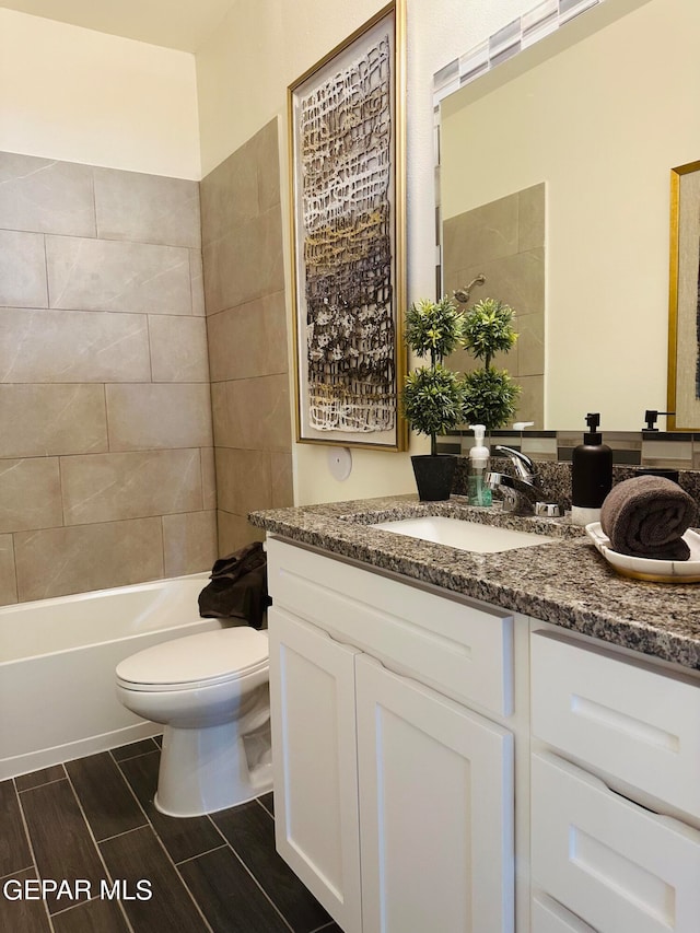 full bathroom with large vanity, toilet, and tiled shower / bath