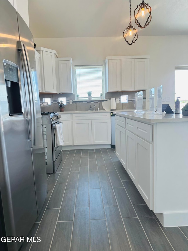 kitchen with white cabinetry, hanging light fixtures, backsplash, appliances with stainless steel finishes, and sink