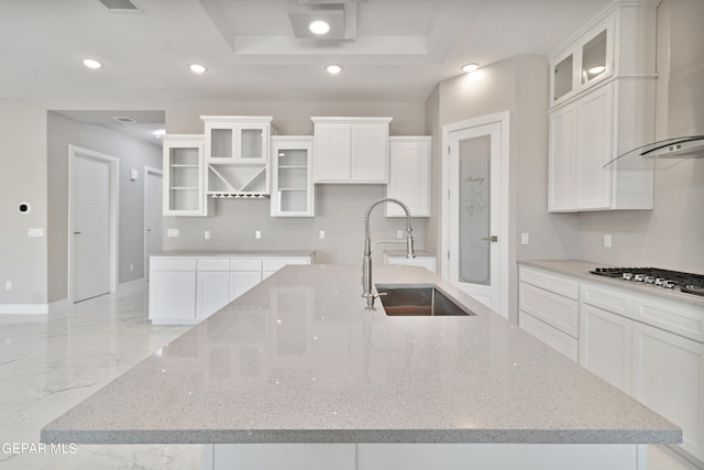 kitchen with a raised ceiling, a large island with sink, stainless steel gas stovetop, a sink, and recessed lighting