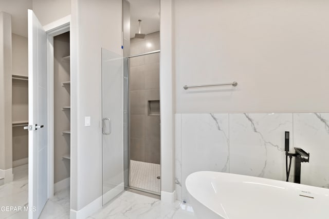 full bath featuring a stall shower, marble finish floor, a soaking tub, and a walk in closet