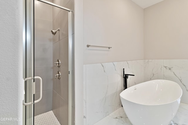 full bath featuring marble finish floor, a stall shower, wainscoting, and a freestanding tub