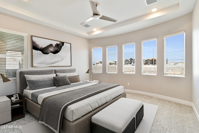 bedroom featuring baseboards, multiple windows, visible vents, and a raised ceiling