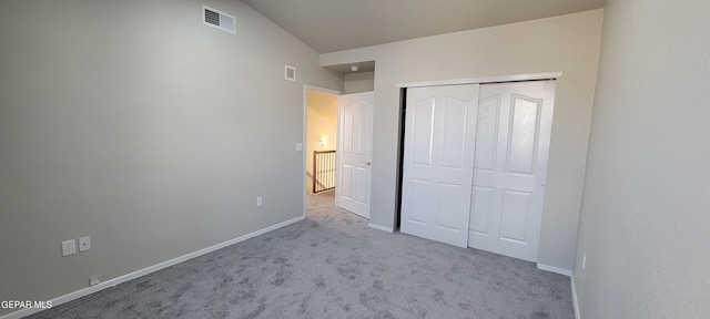 unfurnished bedroom featuring lofted ceiling, a closet, and light colored carpet