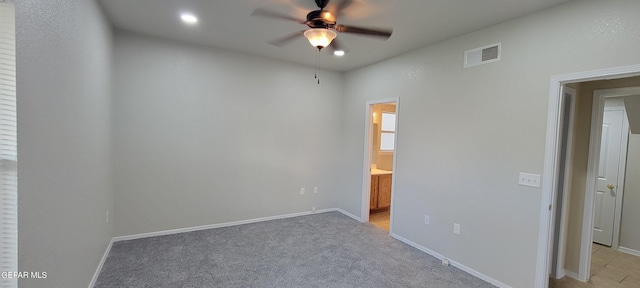 unfurnished bedroom with ceiling fan, light colored carpet, and ensuite bath