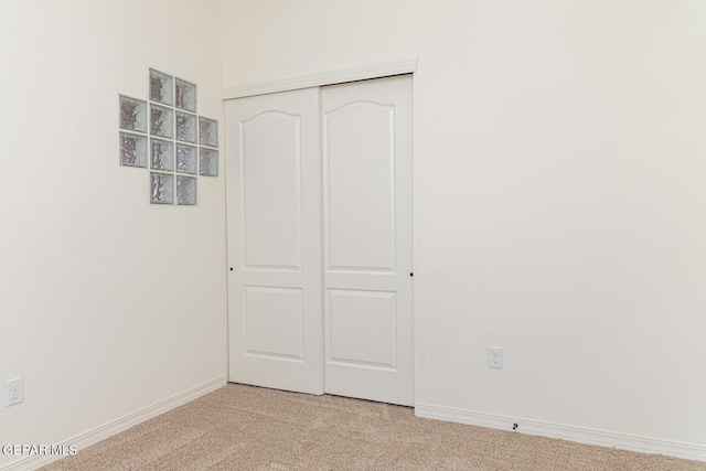 unfurnished bedroom featuring light colored carpet and a closet