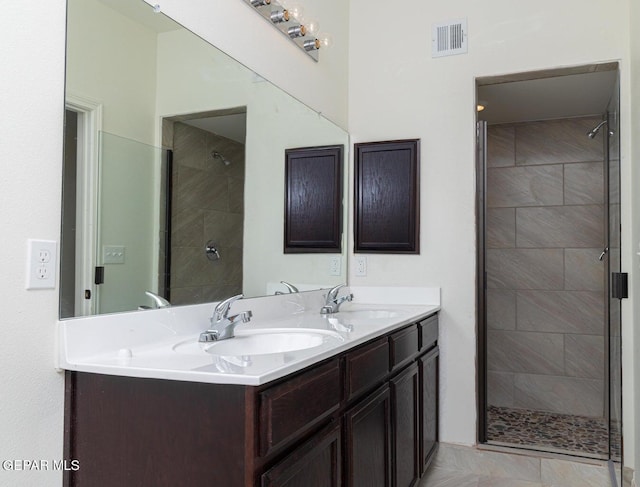 bathroom featuring tiled shower, vanity with extensive cabinet space, dual sinks, and tile floors