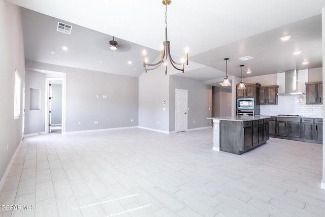 kitchen with visible vents, a kitchen island, stainless steel appliances, wall chimney range hood, and tasteful backsplash