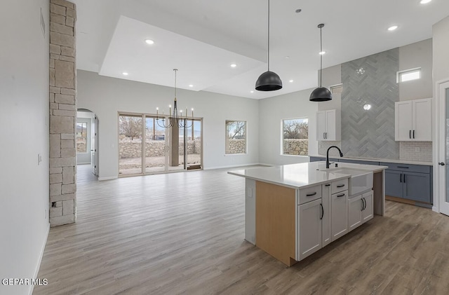 kitchen featuring decorative light fixtures, a center island with sink, sink, and a wealth of natural light