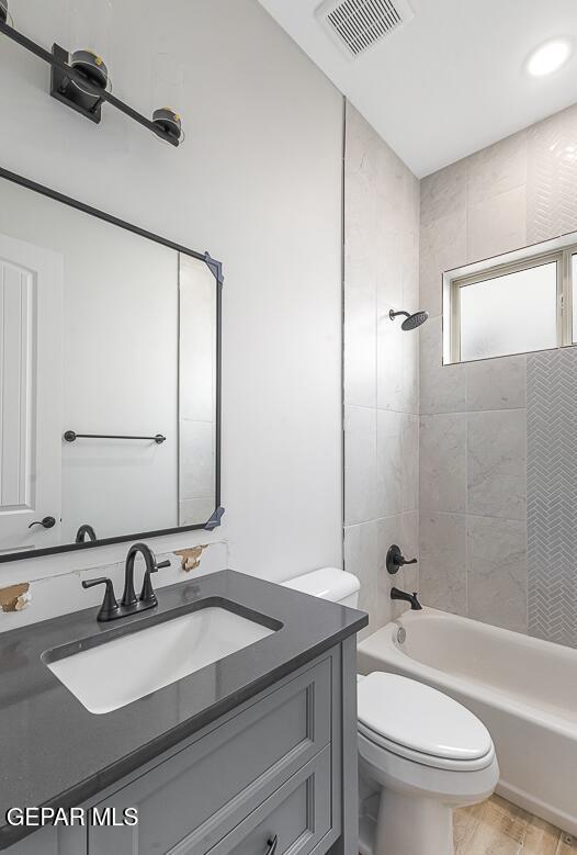 full bathroom featuring vanity, toilet, and tiled shower / bath combo