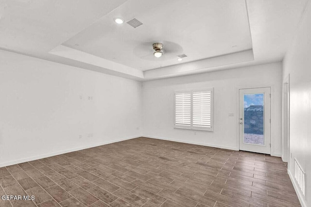 spare room featuring dark hardwood / wood-style flooring, ceiling fan, and a raised ceiling