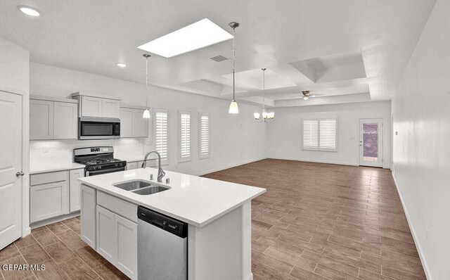 kitchen with appliances with stainless steel finishes, pendant lighting, an island with sink, coffered ceiling, and sink