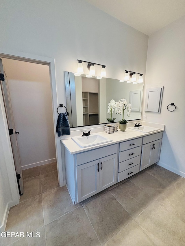 bathroom featuring baseboards, double vanity, and a sink