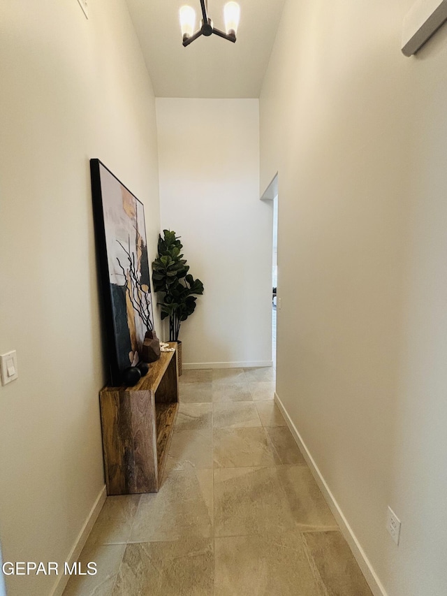 hall with baseboards and a chandelier