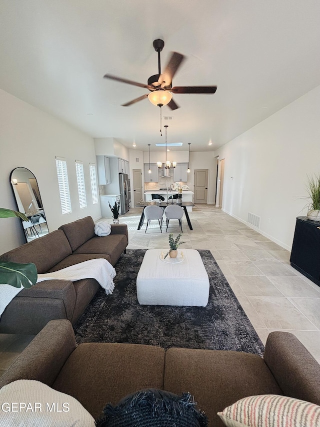 living room with baseboards, visible vents, and ceiling fan with notable chandelier