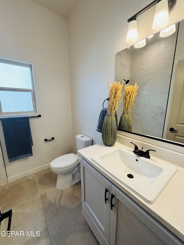 bathroom with baseboards, toilet, and vanity