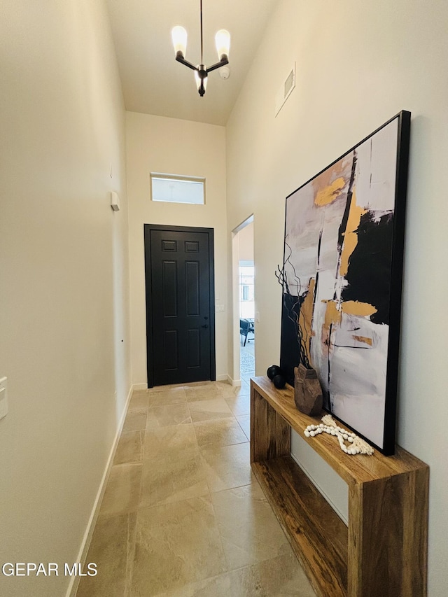 entrance foyer with baseboards, visible vents, a towering ceiling, and an inviting chandelier