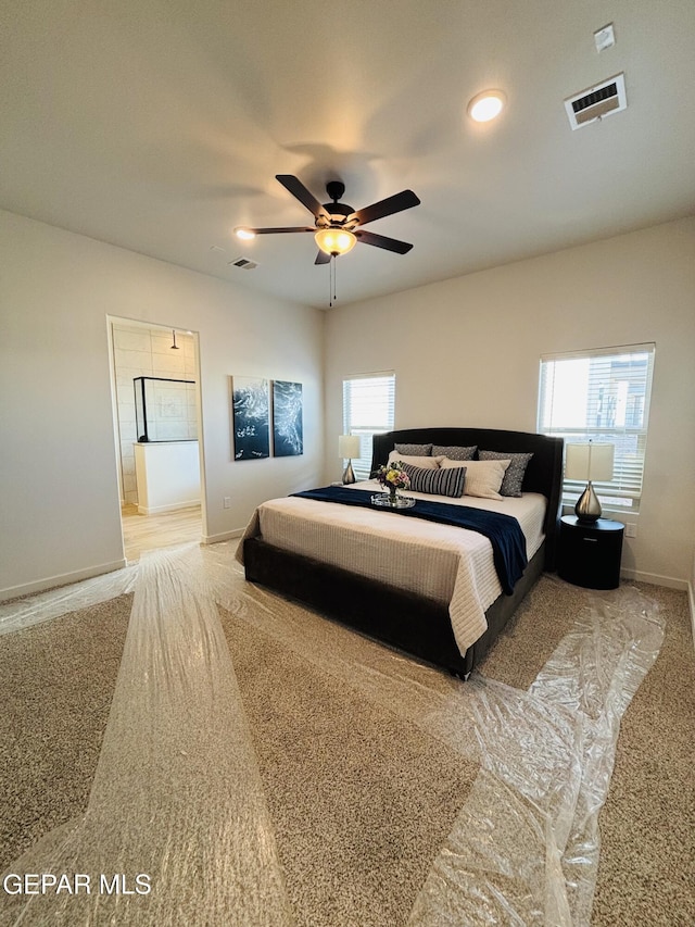 carpeted bedroom featuring connected bathroom, baseboards, visible vents, and a ceiling fan