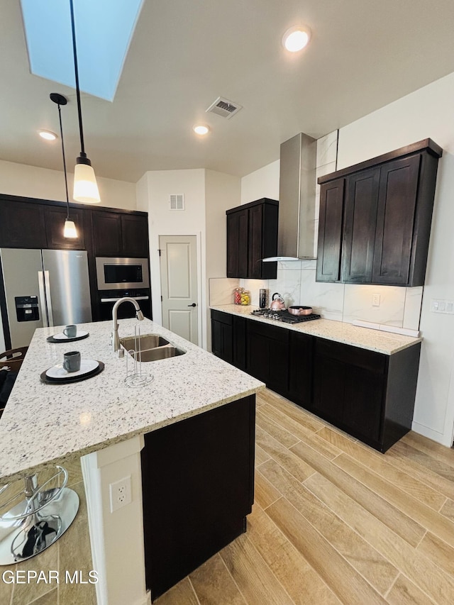 kitchen with a sink, visible vents, light stone counters, and appliances with stainless steel finishes