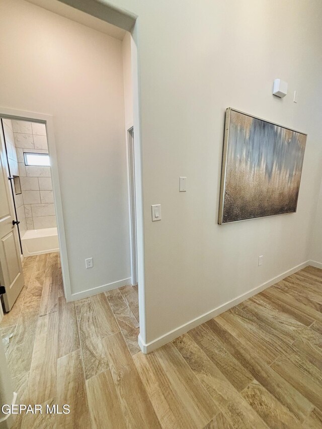 hallway featuring baseboards and light wood finished floors