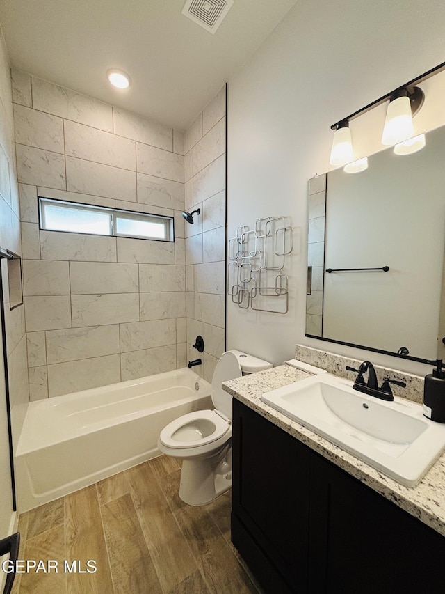 bathroom featuring vanity, toilet, bathing tub / shower combination, visible vents, and wood finished floors