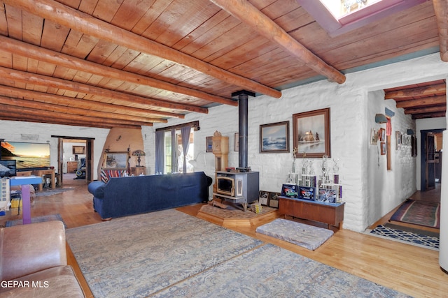 living room with wood ceiling, beam ceiling, hardwood / wood-style floors, and a wood stove