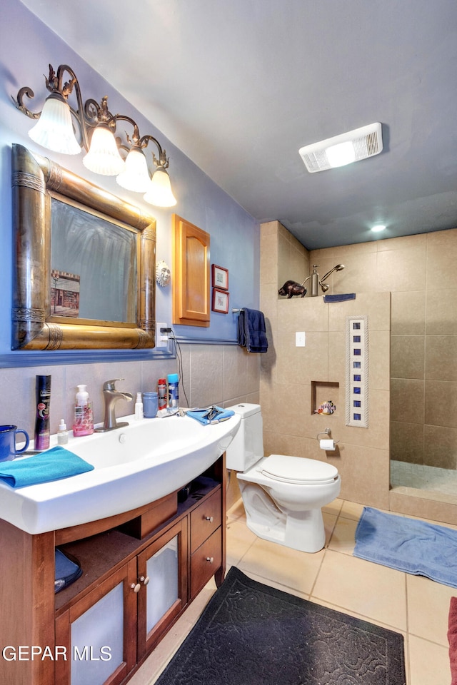 bathroom featuring vanity, tile walls, a tile shower, tile floors, and toilet