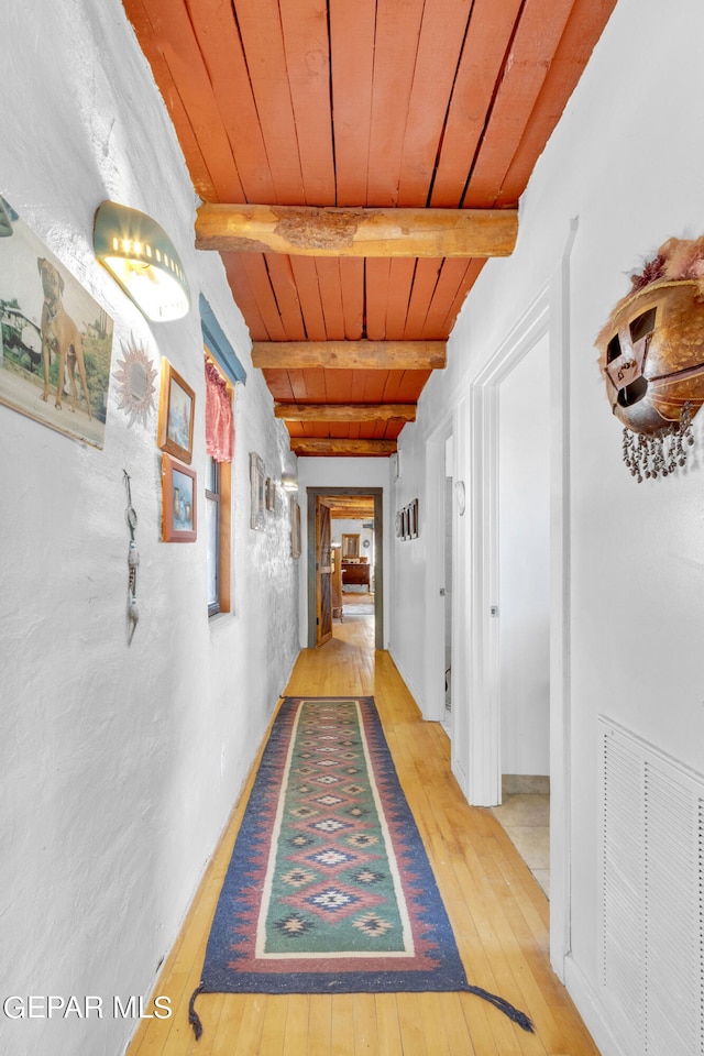 corridor featuring light wood-type flooring, beamed ceiling, and wood ceiling