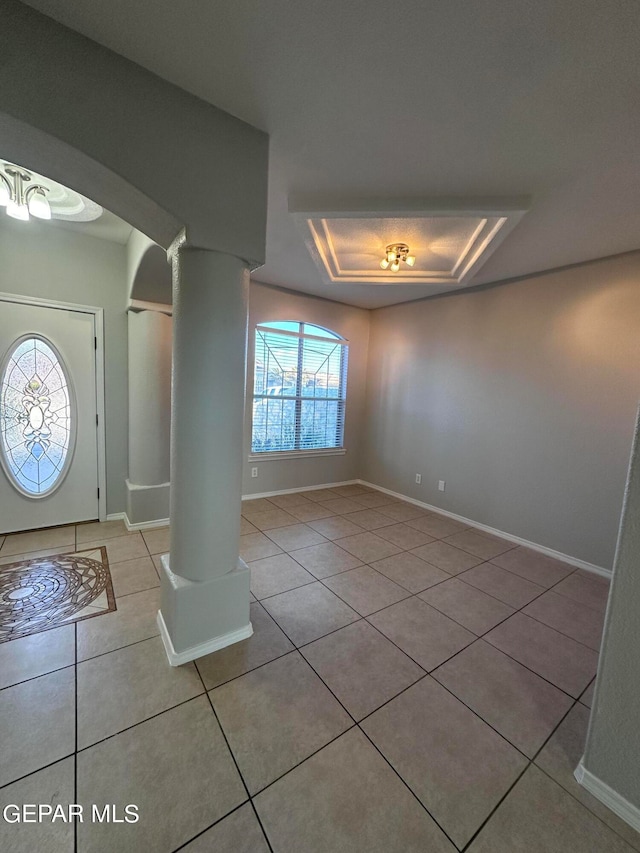 entryway with light tile floors, a healthy amount of sunlight, a tray ceiling, and ornate columns