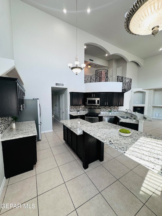 kitchen with light tile floors, hanging light fixtures, appliances with stainless steel finishes, tasteful backsplash, and a notable chandelier