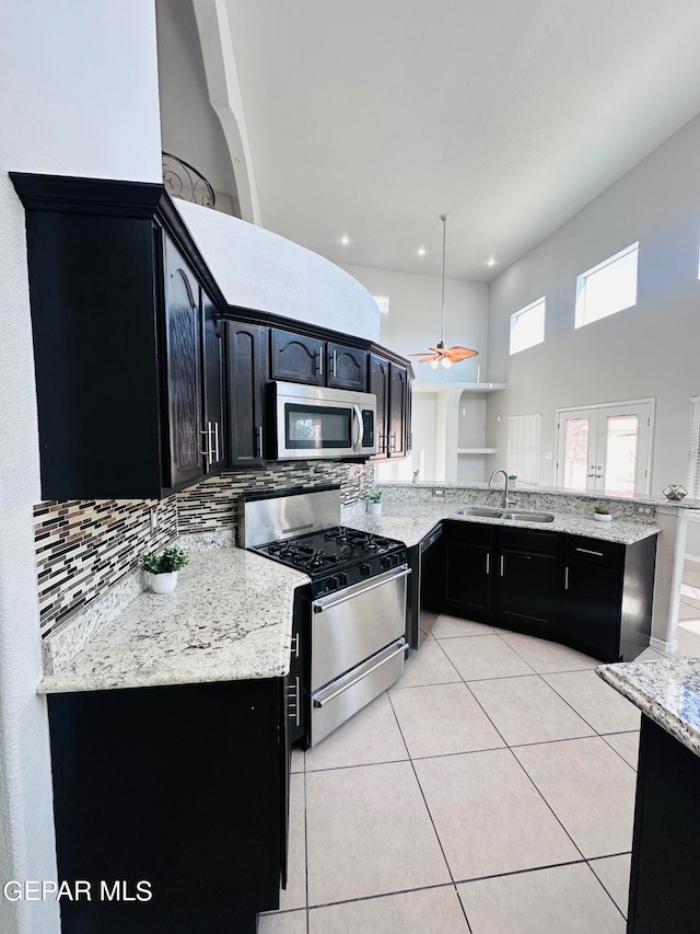 kitchen featuring kitchen peninsula, ceiling fan, gas stove, sink, and tasteful backsplash