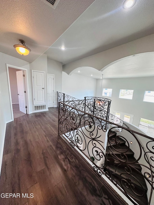 hall featuring a textured ceiling and dark hardwood / wood-style flooring