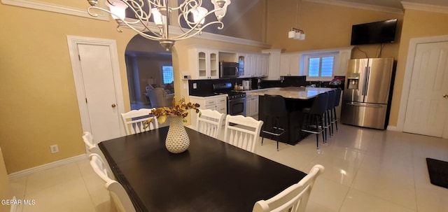 kitchen with a breakfast bar, stainless steel appliances, light tile floors, white cabinets, and a chandelier