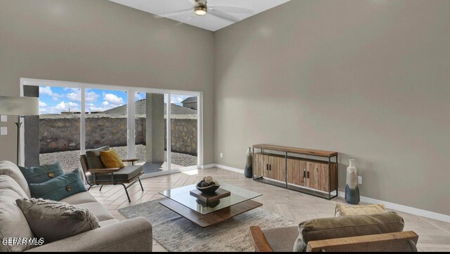 living room with light parquet flooring, ceiling fan, and a towering ceiling