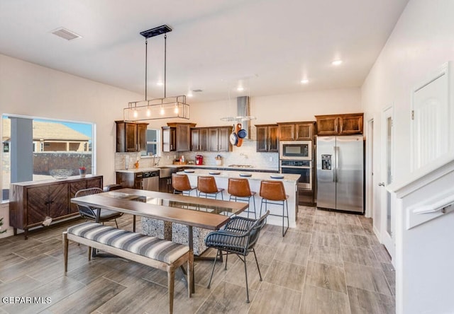 kitchen featuring tasteful backsplash, stainless steel appliances, decorative light fixtures, and a center island