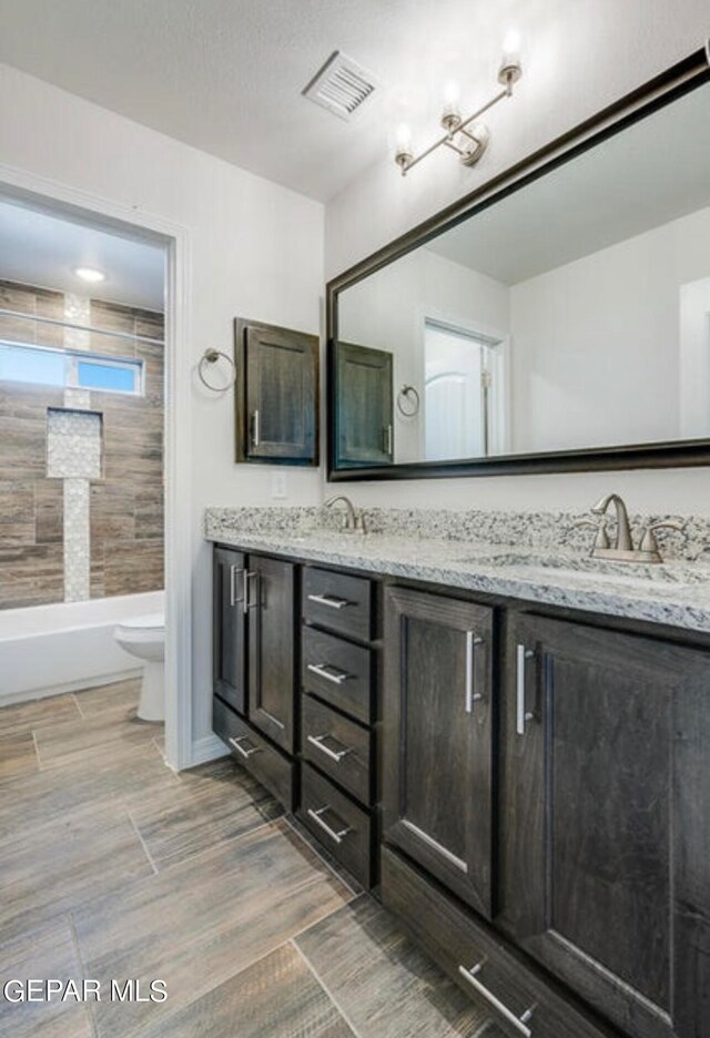 bathroom with tile flooring, double sink, toilet, and large vanity