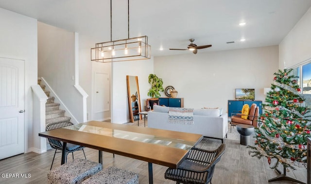 dining room with ceiling fan with notable chandelier and light hardwood / wood-style flooring