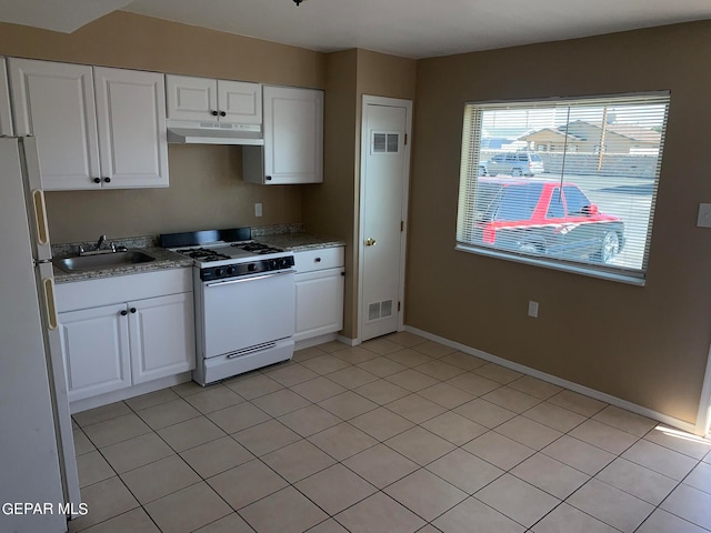 kitchen with stainless steel fridge, gas range gas stove, white cabinets, and light tile floors