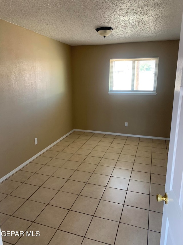 spare room with a textured ceiling and light tile flooring