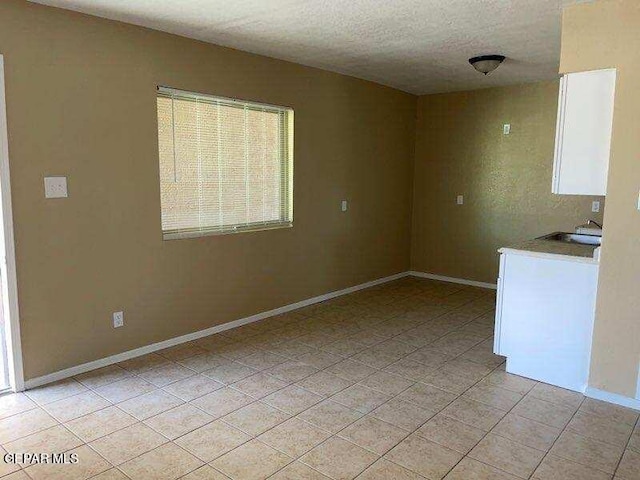 tiled empty room featuring a textured ceiling and sink