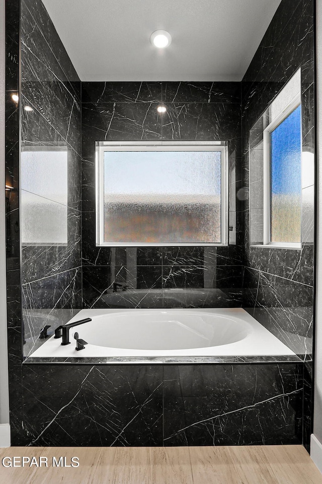 bathroom featuring tiled bath and tile walls