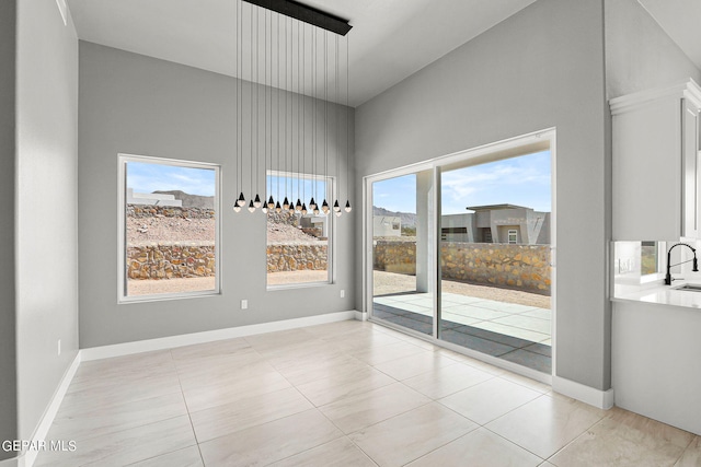 spare room with a towering ceiling, plenty of natural light, sink, and light tile patterned floors