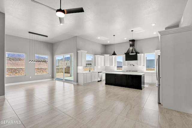 kitchen with a kitchen island, ceiling fan, stainless steel appliances, white cabinetry, and decorative light fixtures