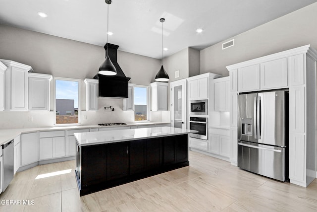 kitchen featuring white cabinets, hanging light fixtures, a kitchen island, stainless steel appliances, and custom range hood